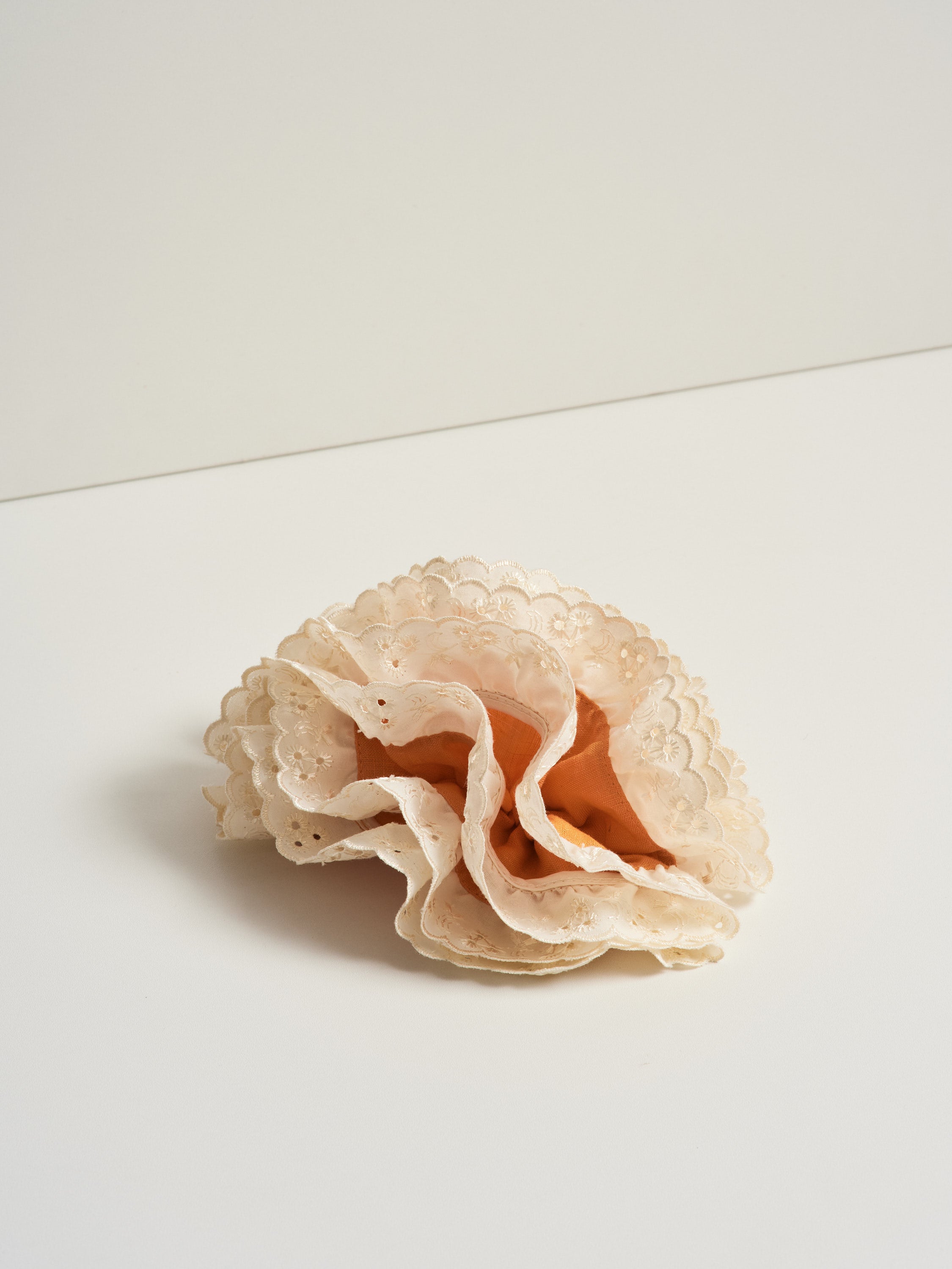 Azalea hair clip featuring guava orange linen and off-white eyelet lace, placed over a white surface for product photography.
