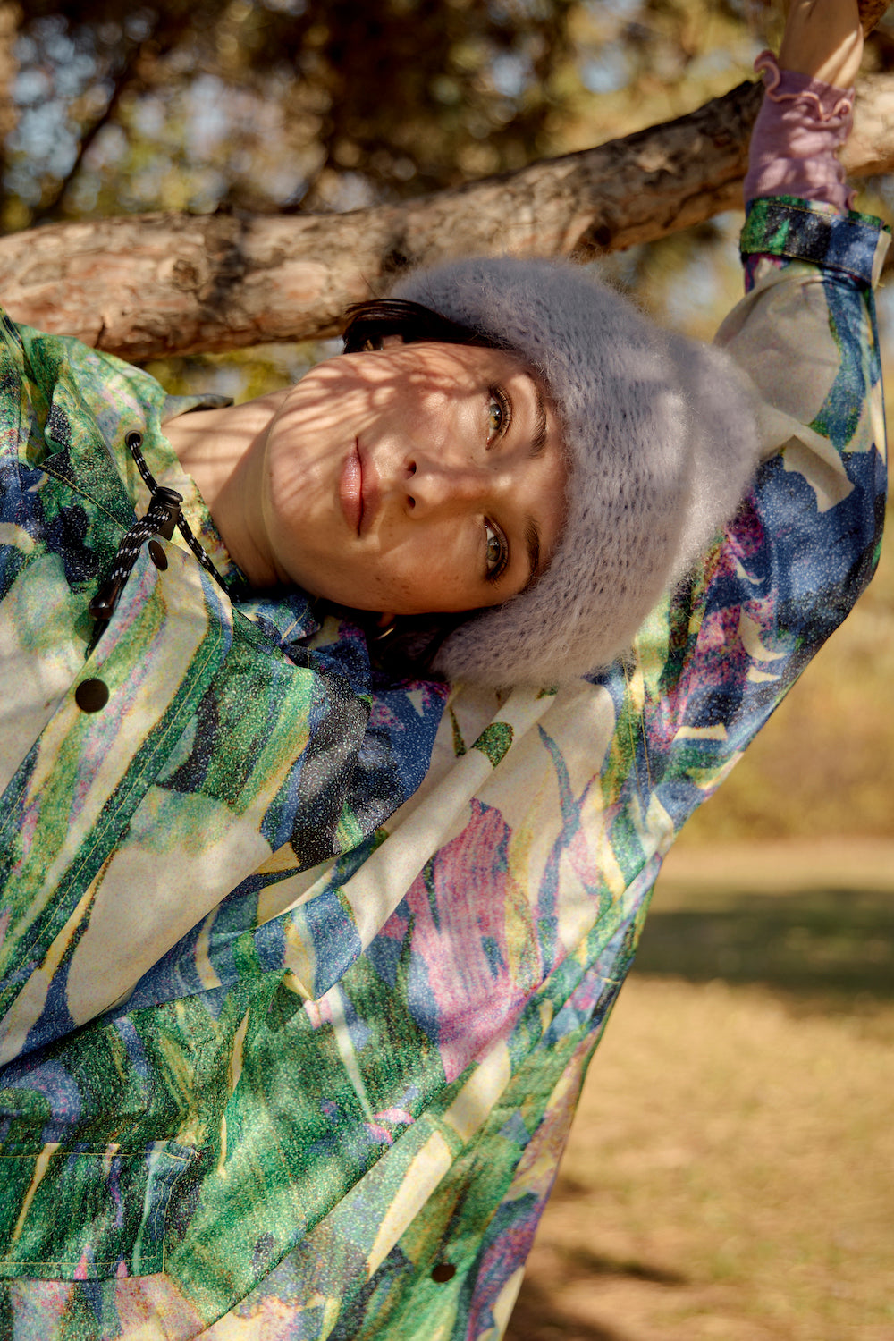 Model wearing a lilac mohair beanie, with tree branch shadows gently cast on her face, creating a soft, natural look.