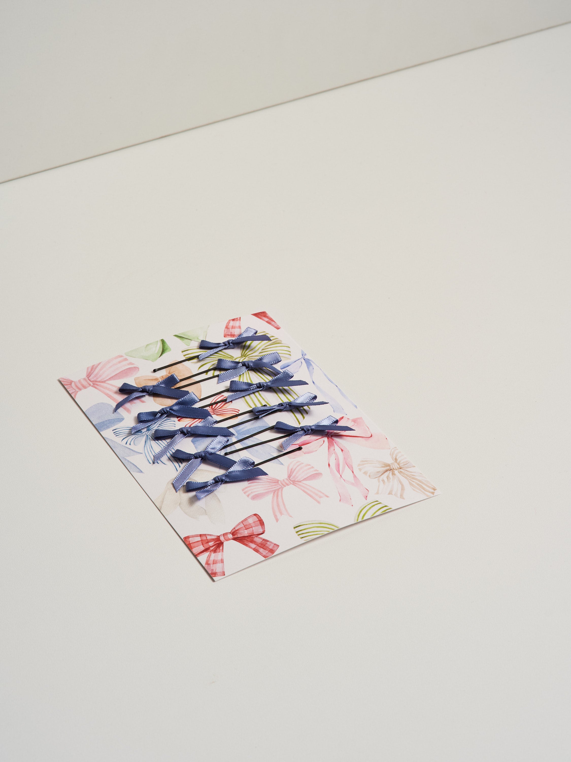 Light blue satin bow hair slides displayed on card stock and pictured on a white background.