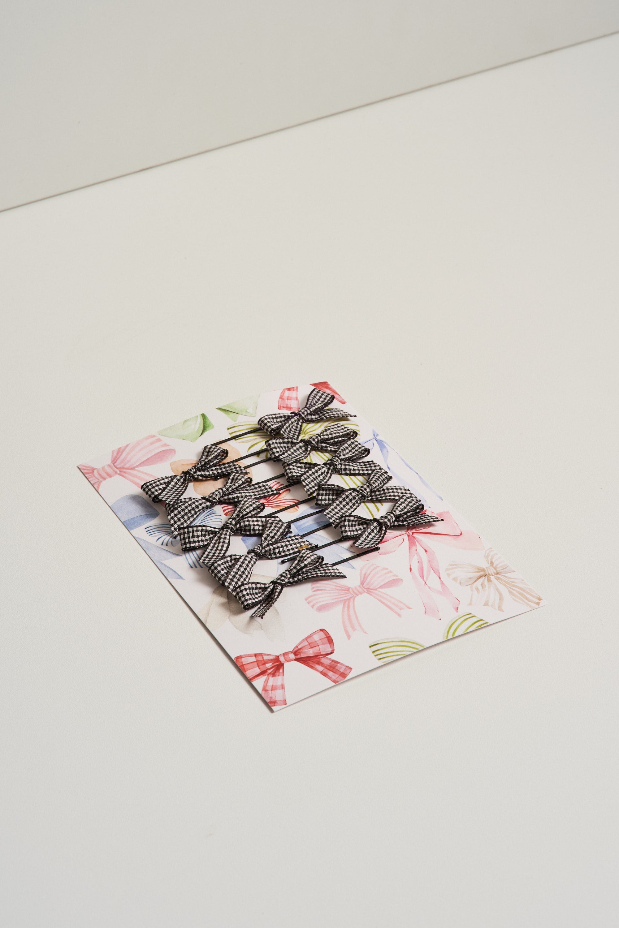 Gingham ribbon bow hair slides displayed on card stock and pictured on a white background.
