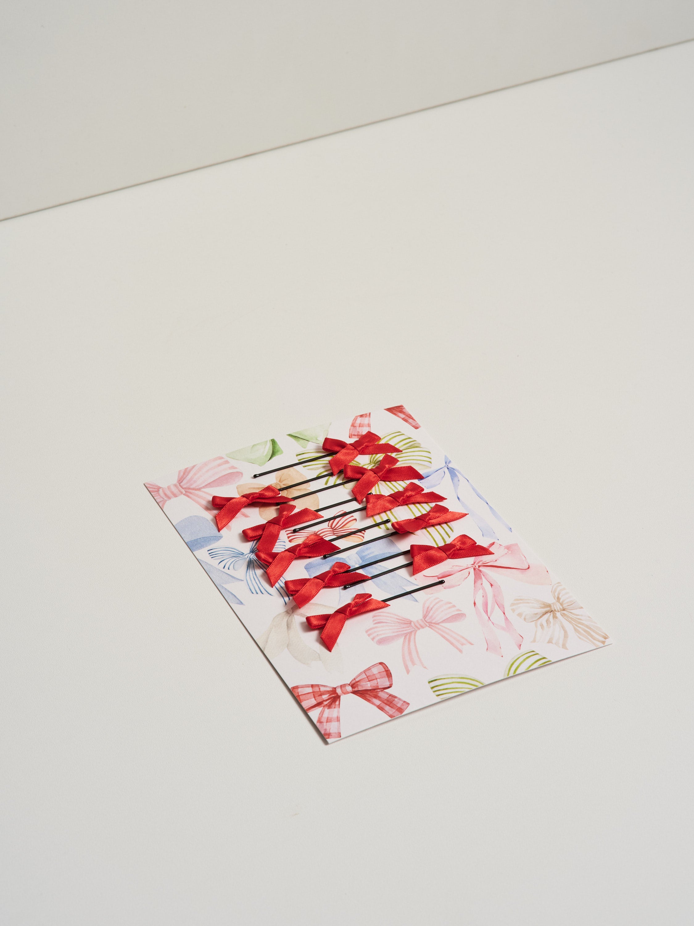 Red satin bow hair slides displayed on card stock and pictured on a white background.