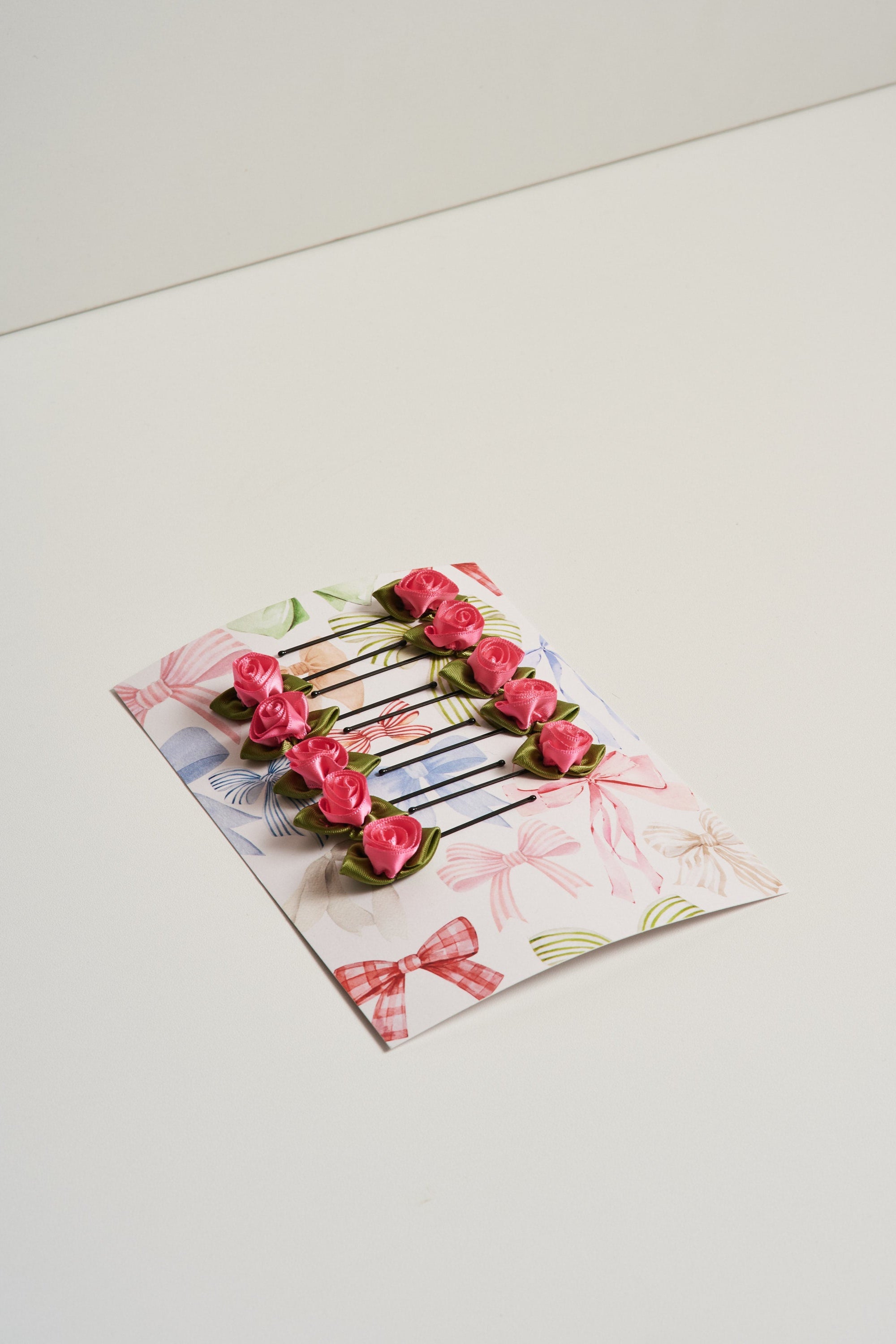10 satin rosette hair slides displayed on cardstock and pictures on a white background.