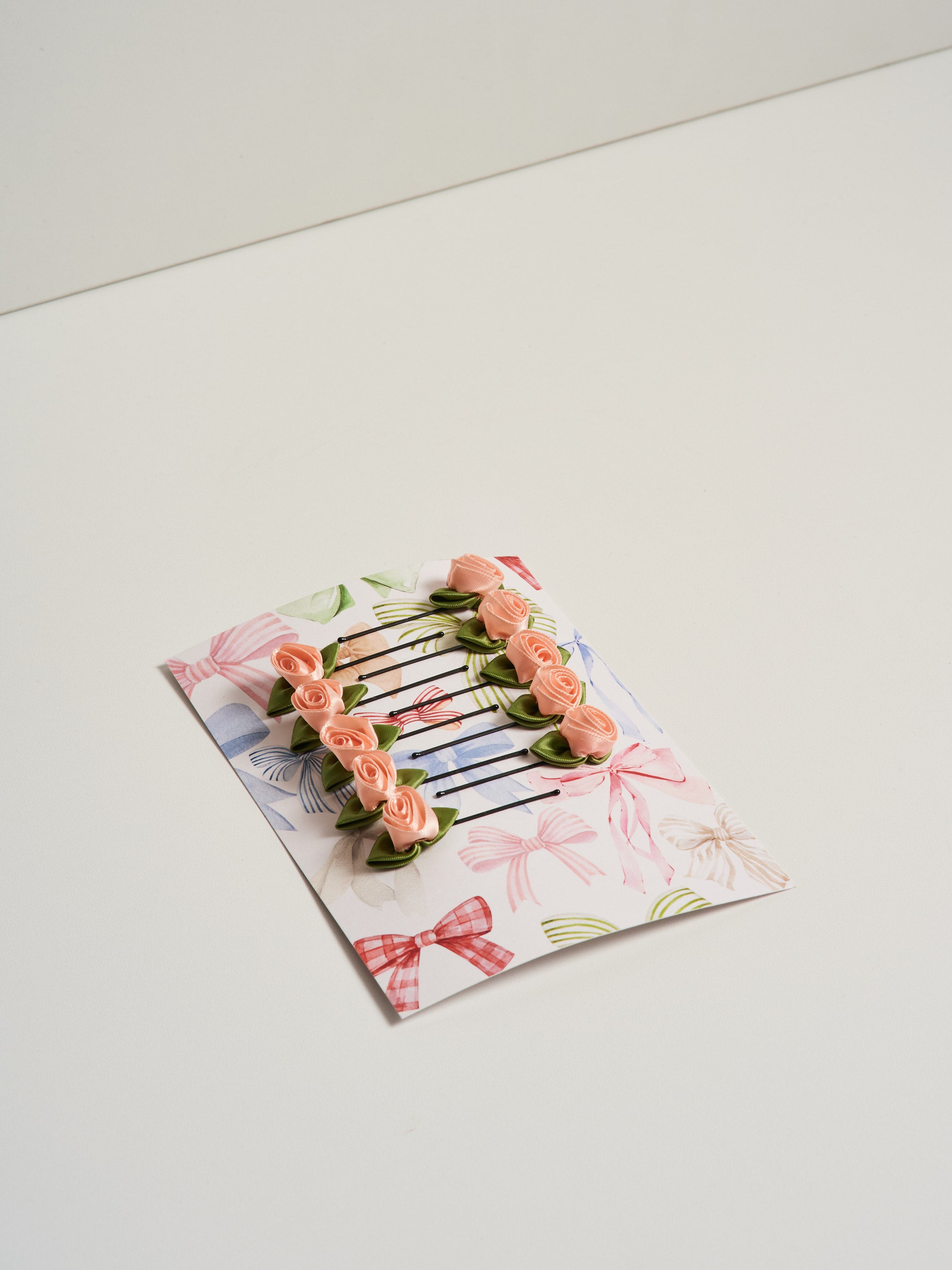 10 pink satin rosette hair slides displayed on cardstock and pictures on a white background.