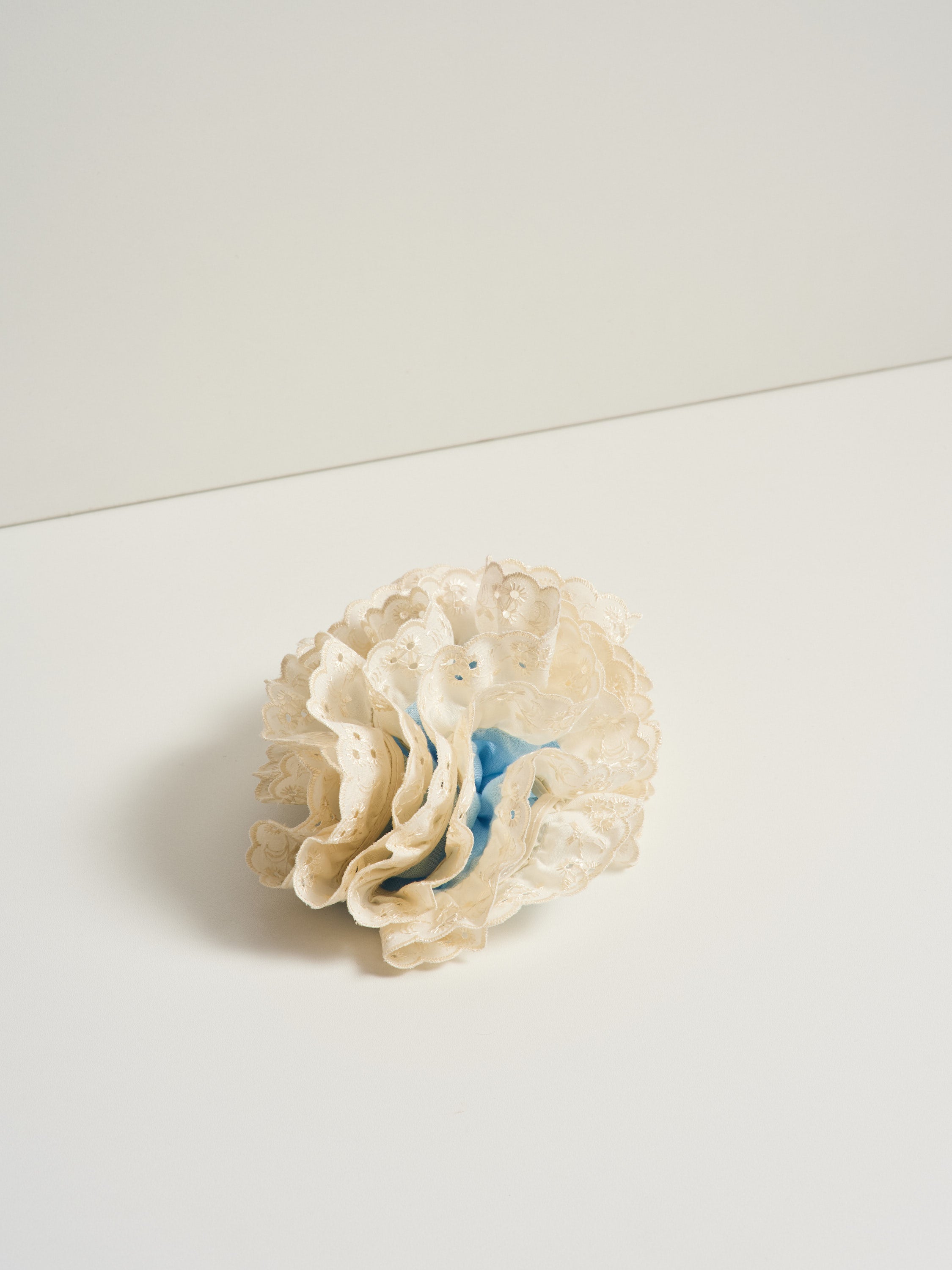 Azalea hair clip featuring light blue linen and off-white eyelet lace, placed over a white surface for product photography.
