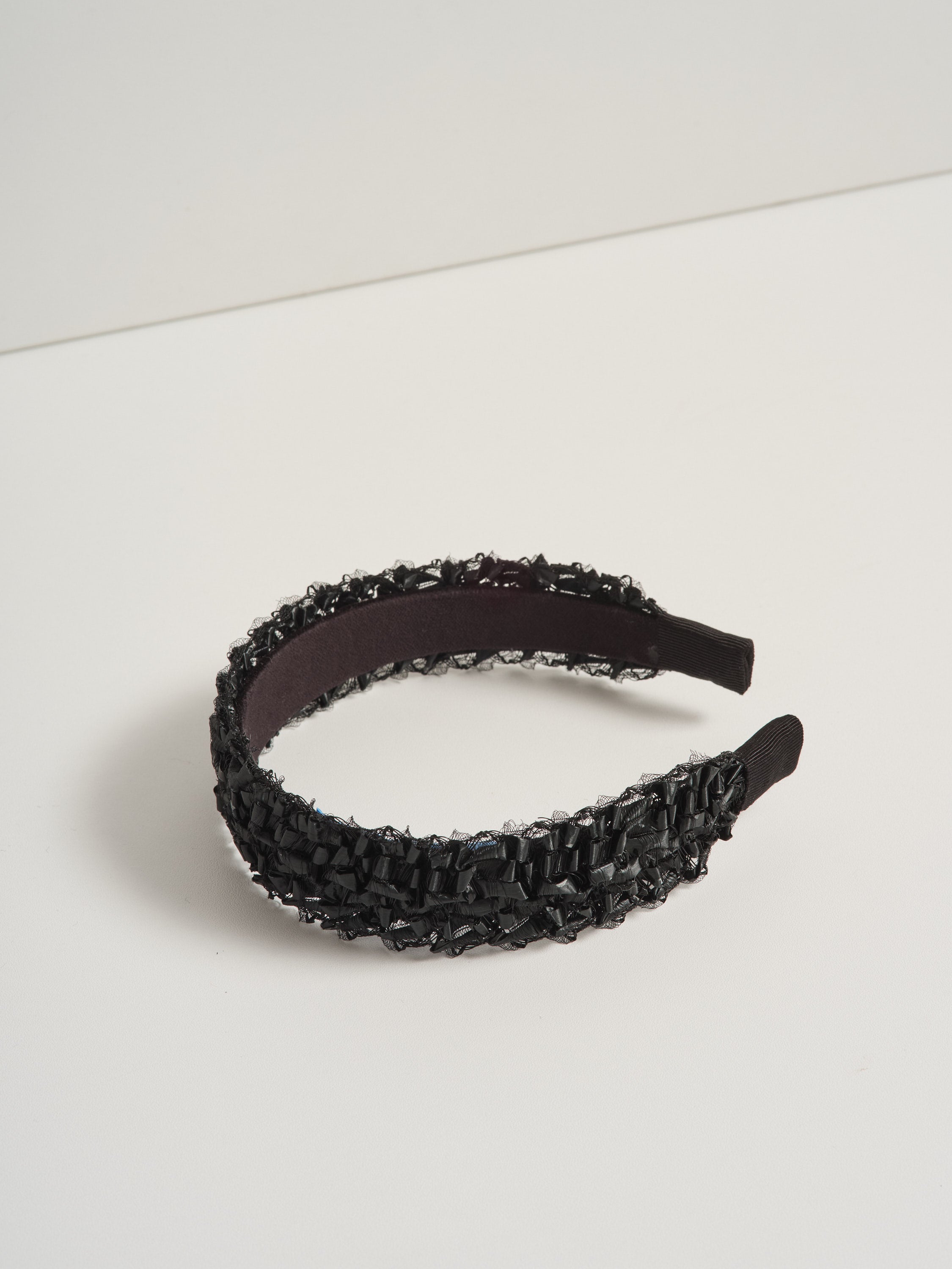 Black straw headband pictured on a white background.