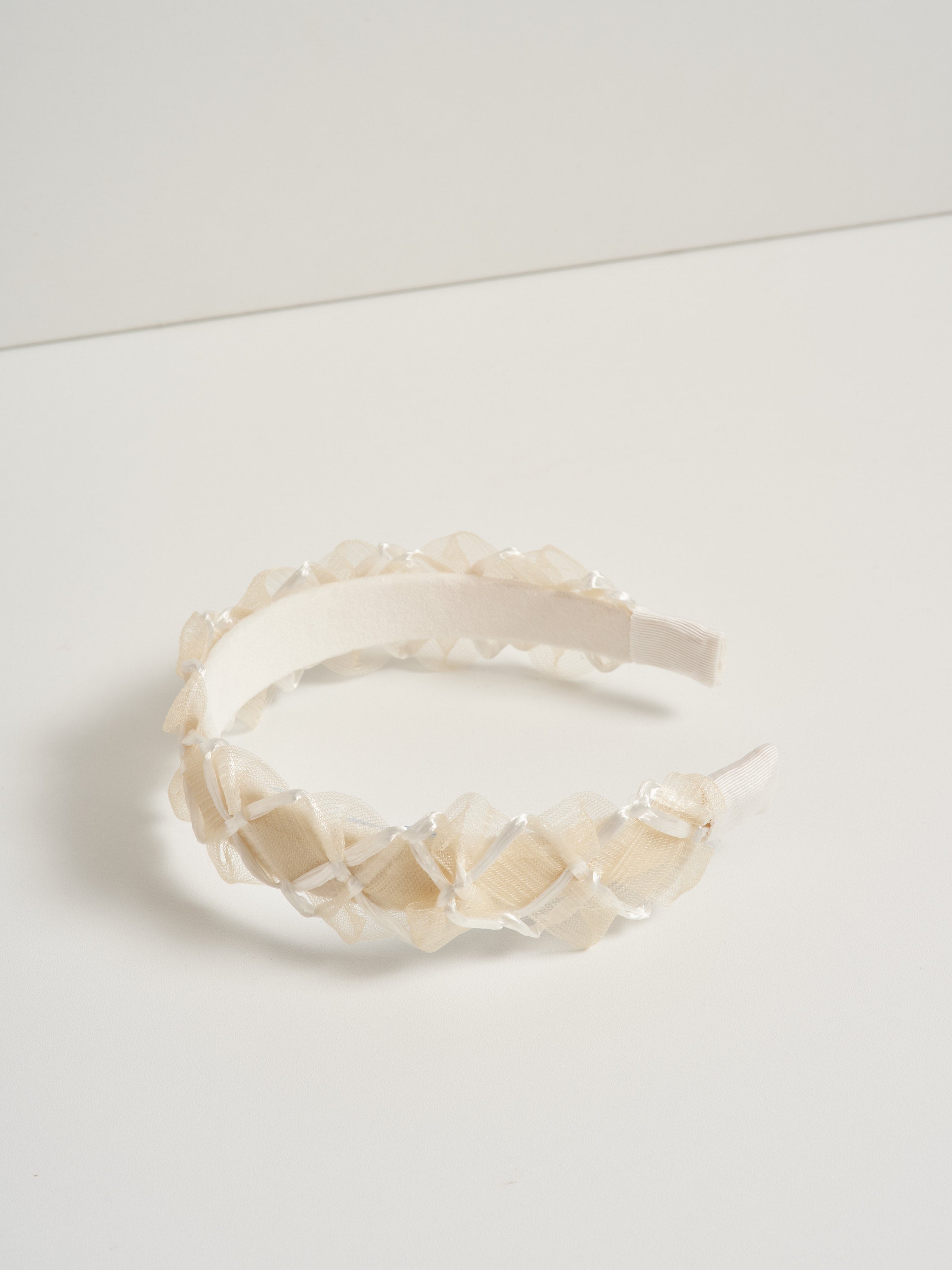 An off white headband made with deadstock straw by heirloom hats, pictured on a white background.